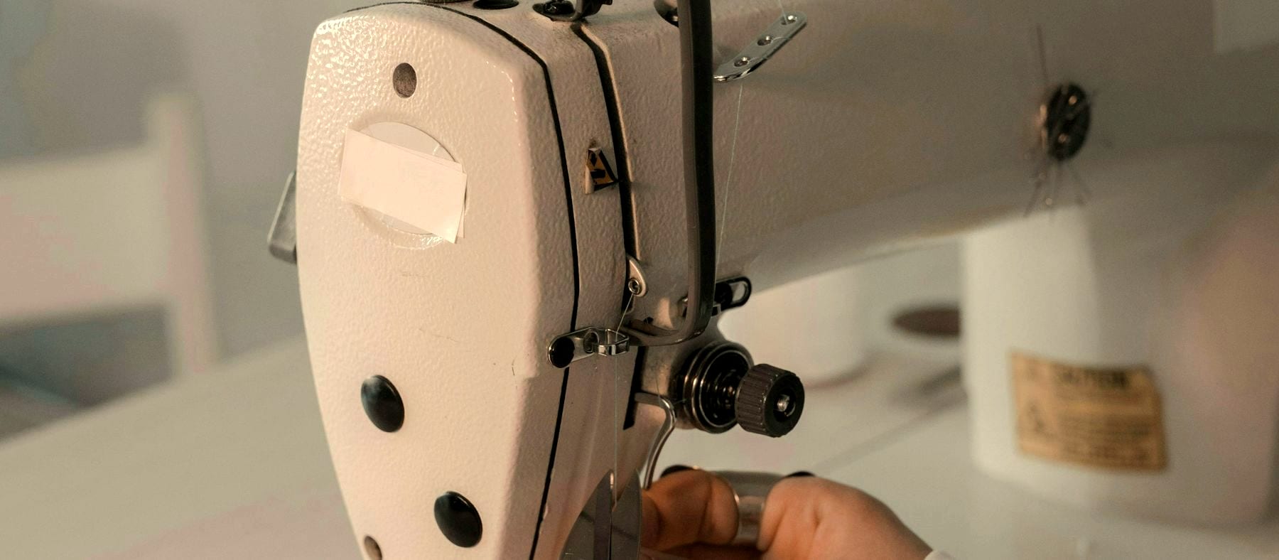 Hands guiding cloth through an industrial sewing machine