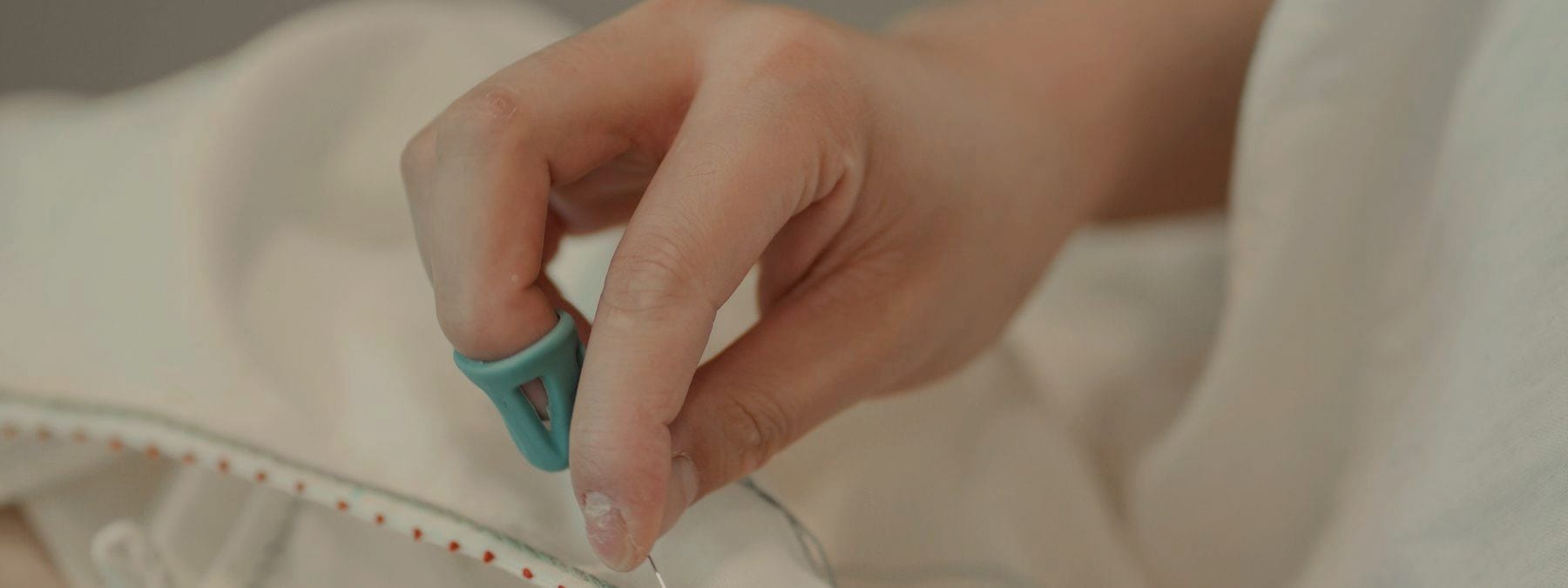 Hands finishing a hem by hand with a needle